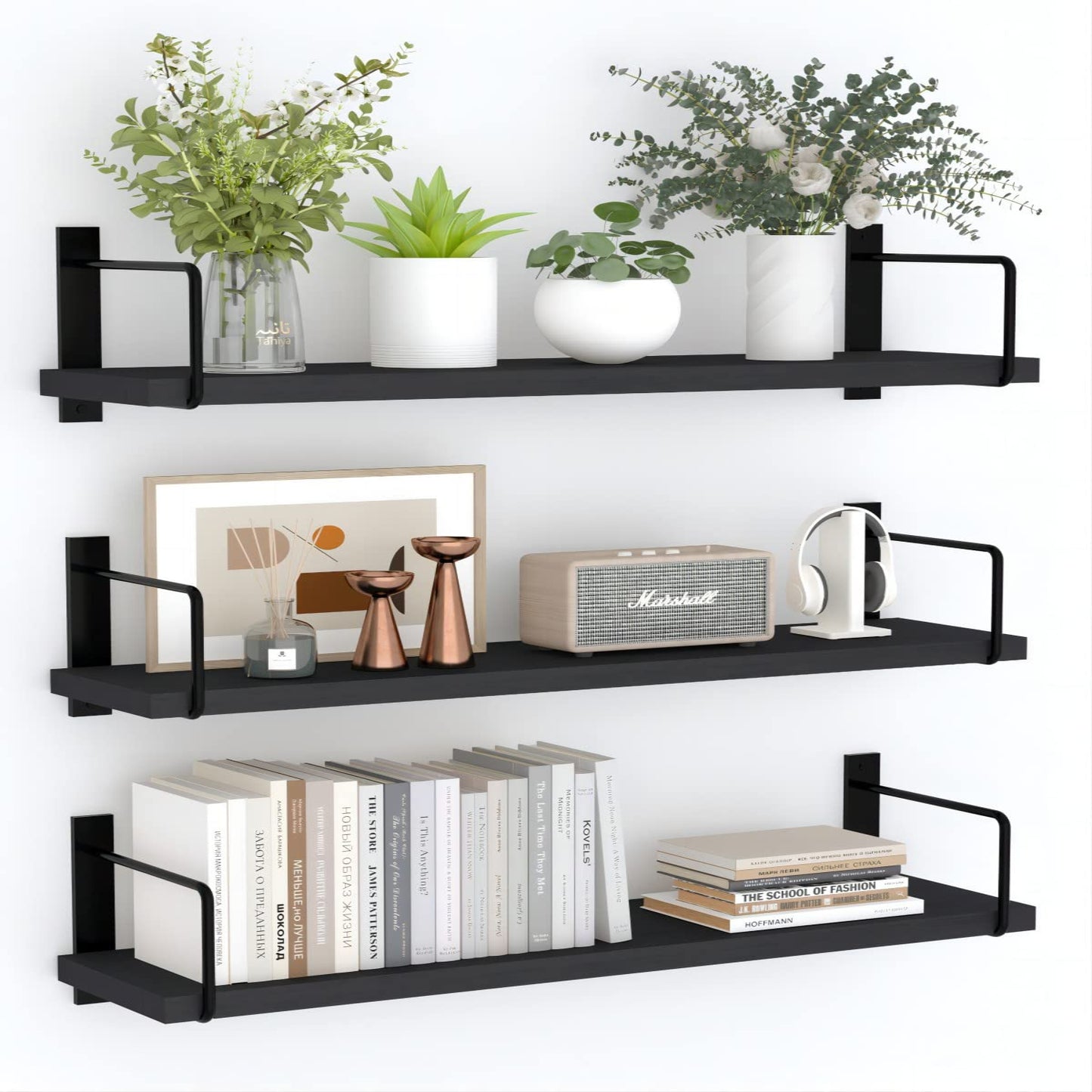 Black wall shelves with books, plants, and decor items on a white background