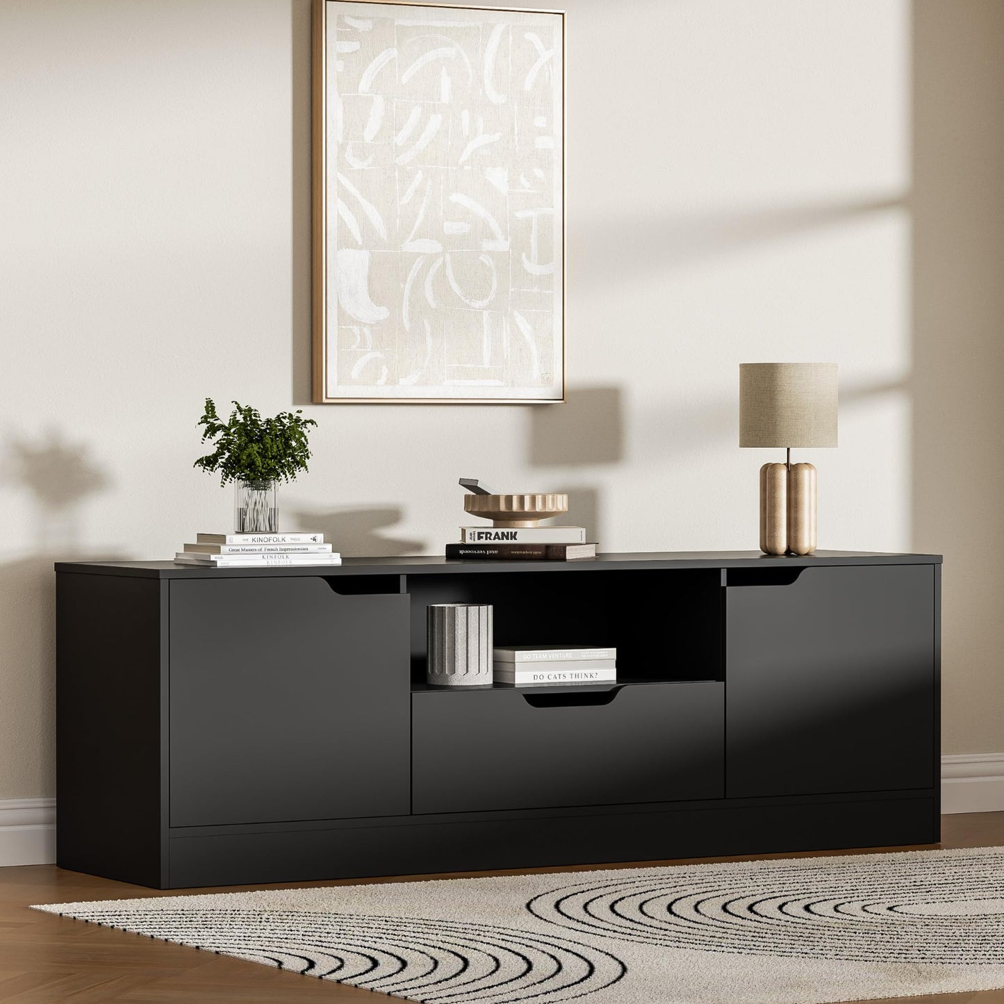Black high-gloss entertainment console with decor items in a living room setting.