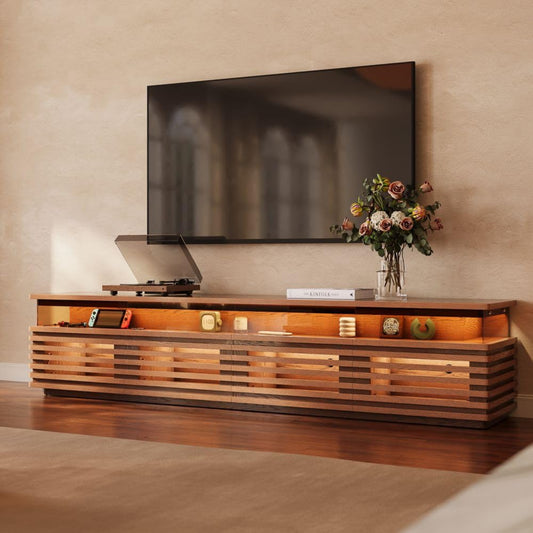 Wooden TV stand with a television and decorative items against a beige wall.