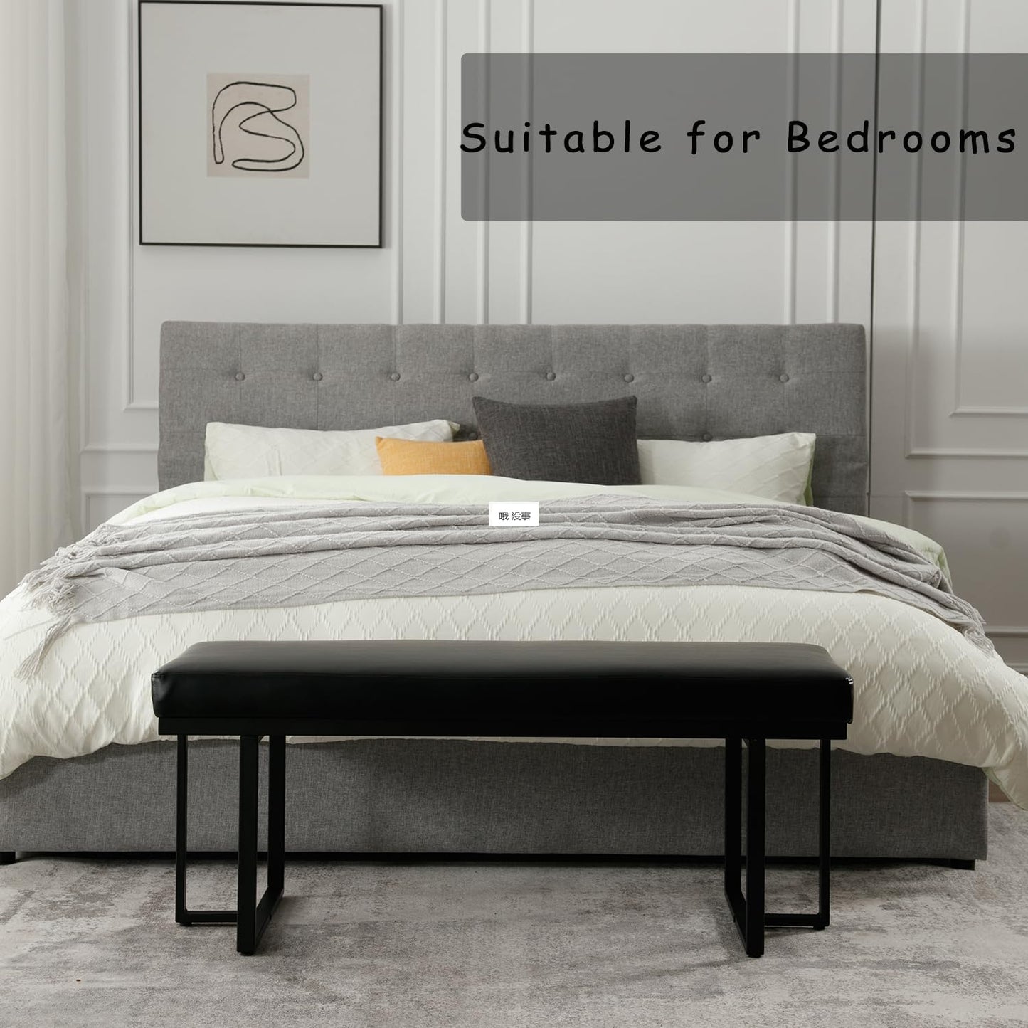 Gray upholstered bed with white bedding and a black bench in a bedroom setting.