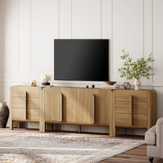 A light oak wood media console in a modern living room setting, styled with a black flat-screen TV, decorative objects, a potted plant, and a patterned area rug.