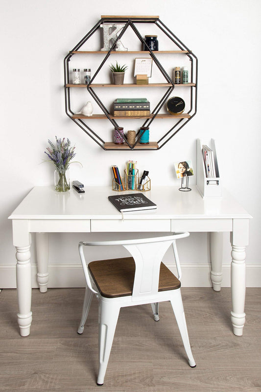 White desk with a chair, geometric shelf above, and various items on a wooden floor.