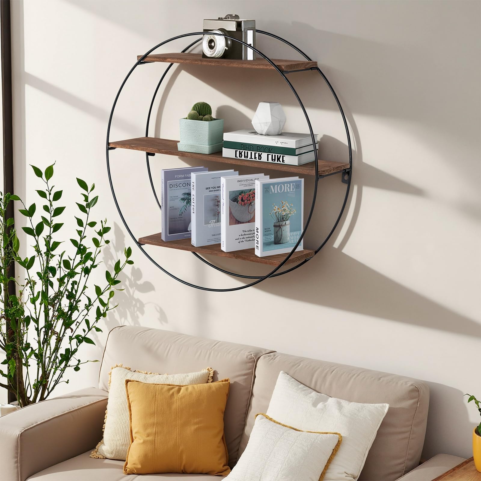 Round wall shelf with books and decor items above a sofa with cushions.