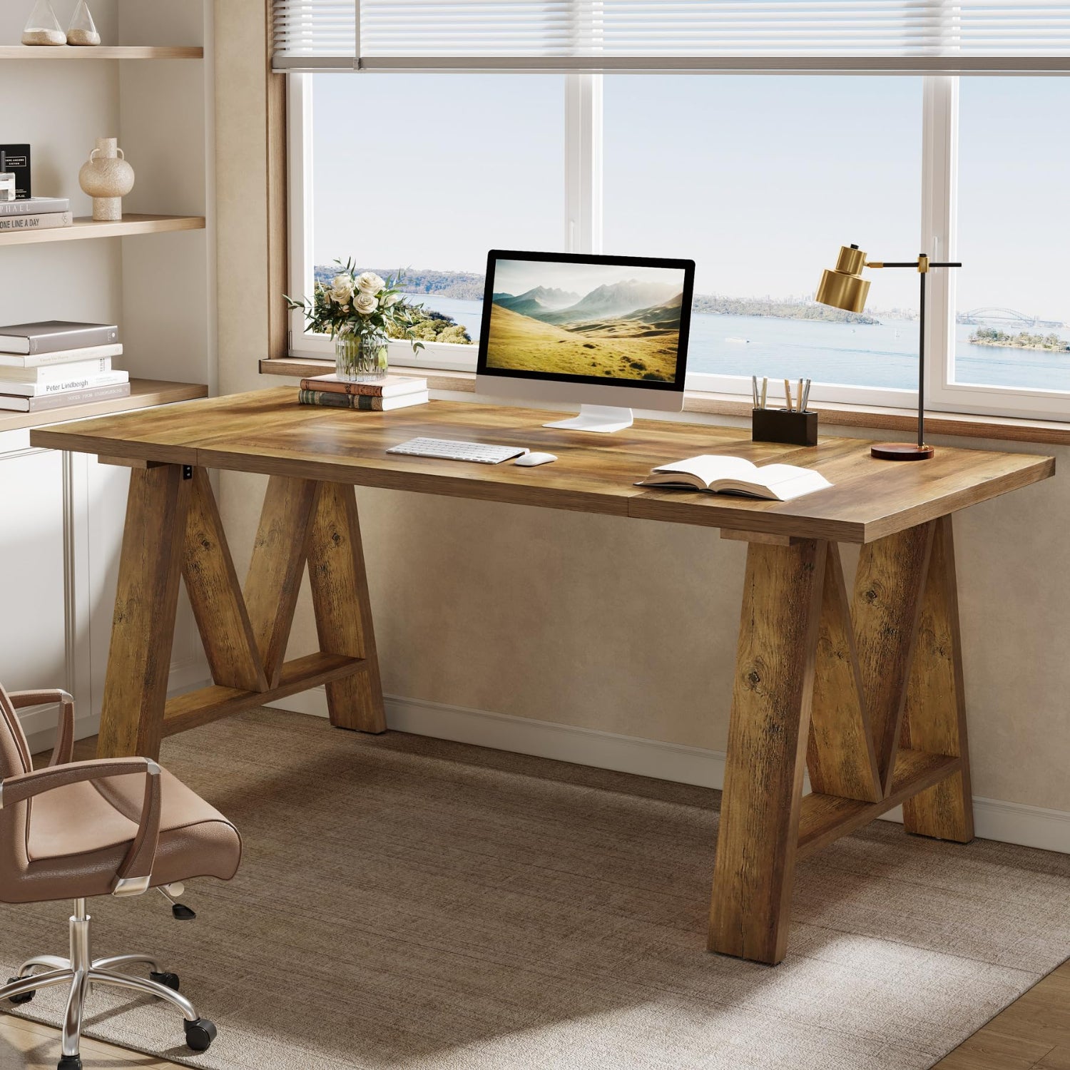 Wooden desk with office items in a bright room with large windows.