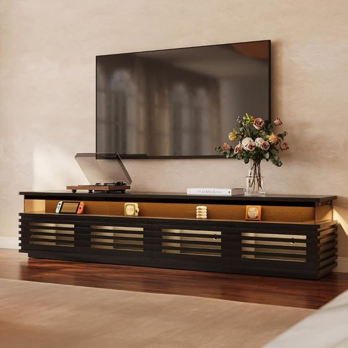 Modern entertainment console with a television and decorative items against a beige wall.