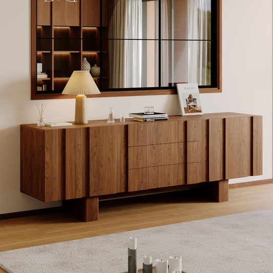 A modern wooden sideboard or credenza with a warm medium-brown finish, featuring a grid pattern of doors and drawers, styled in a minimalist interior with a table lamp, books, and a mirror above.
