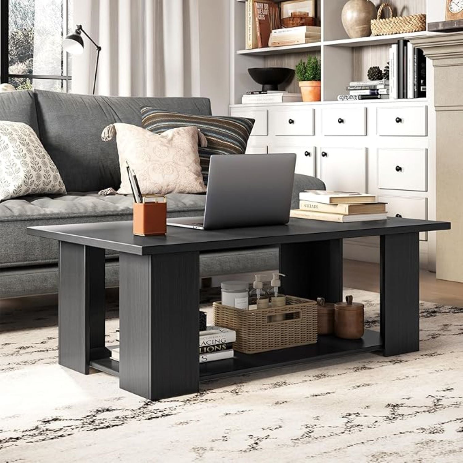 Black coffee table with a laptop, books, and decorative items in a living room setting.