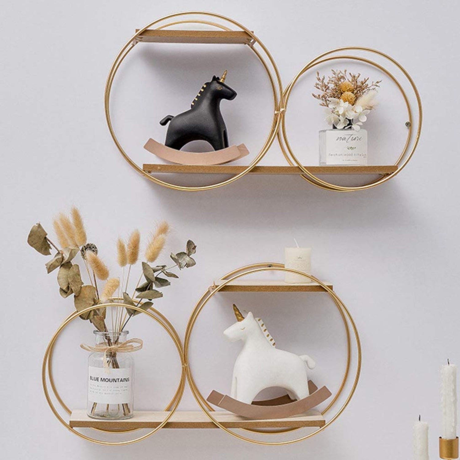 Decorative wall shelves with circular gold frames, unicorn figurines, and plants on a white wall.