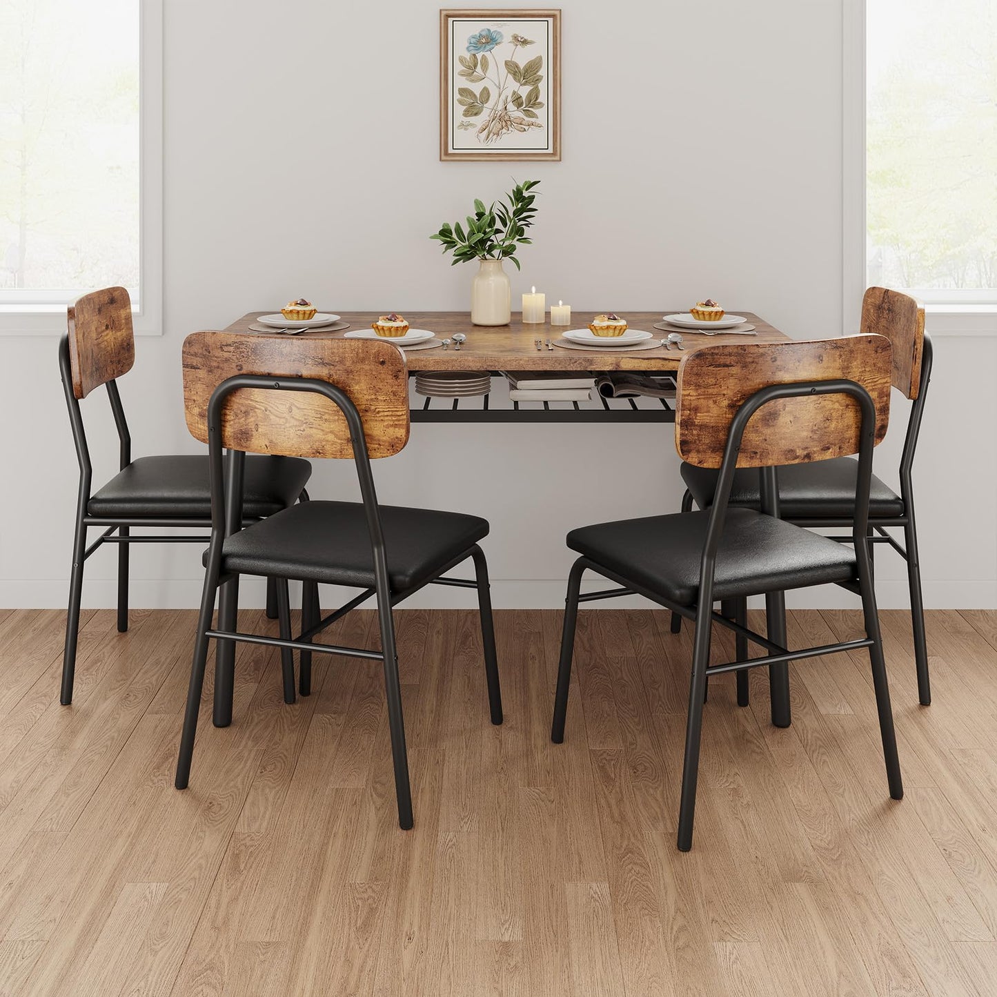 Dining table set with wooden chairs and black seats in a room with a plant and framed picture on the wall.