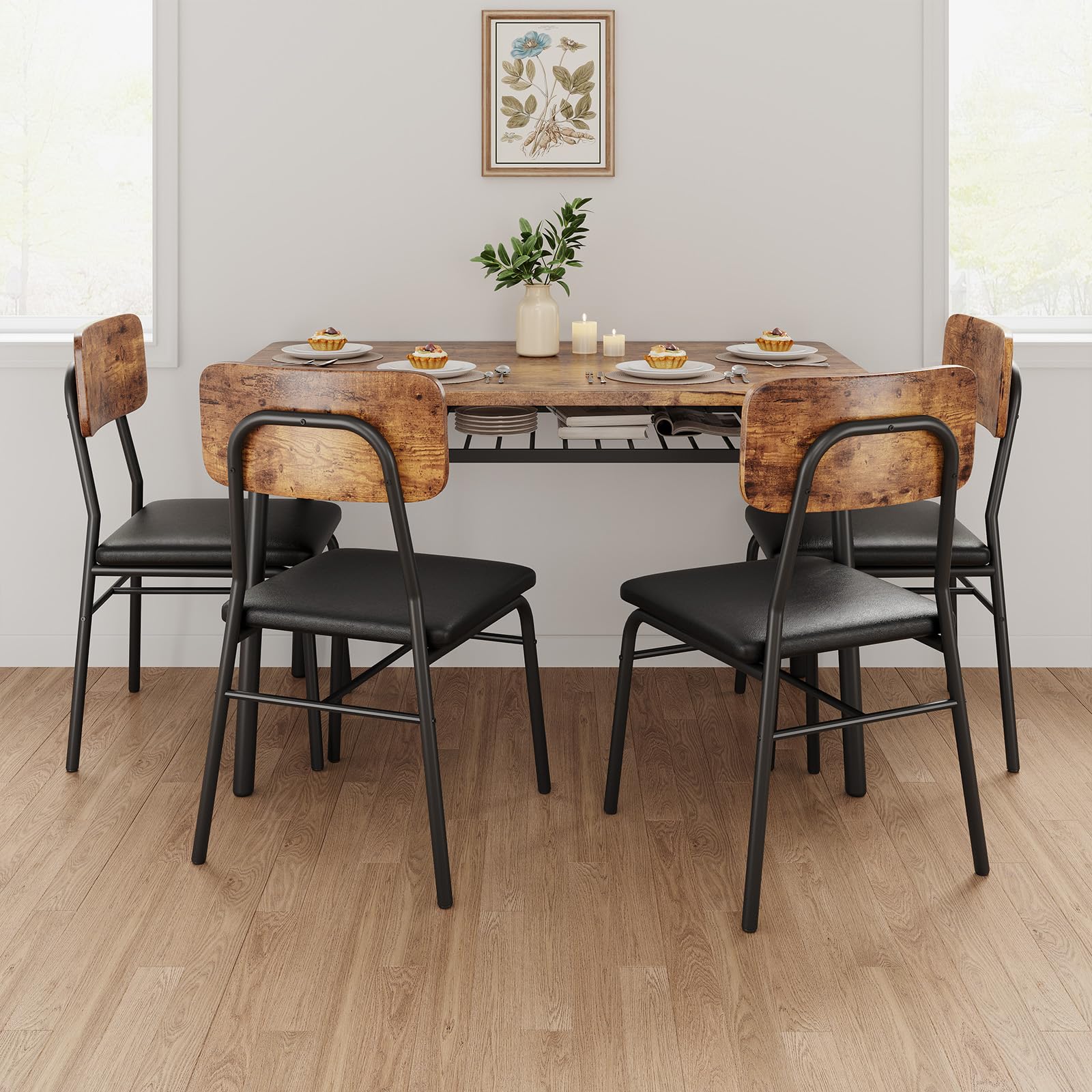 Dining table set with wooden chairs and black seats in a room with a plant and framed picture on the wall.