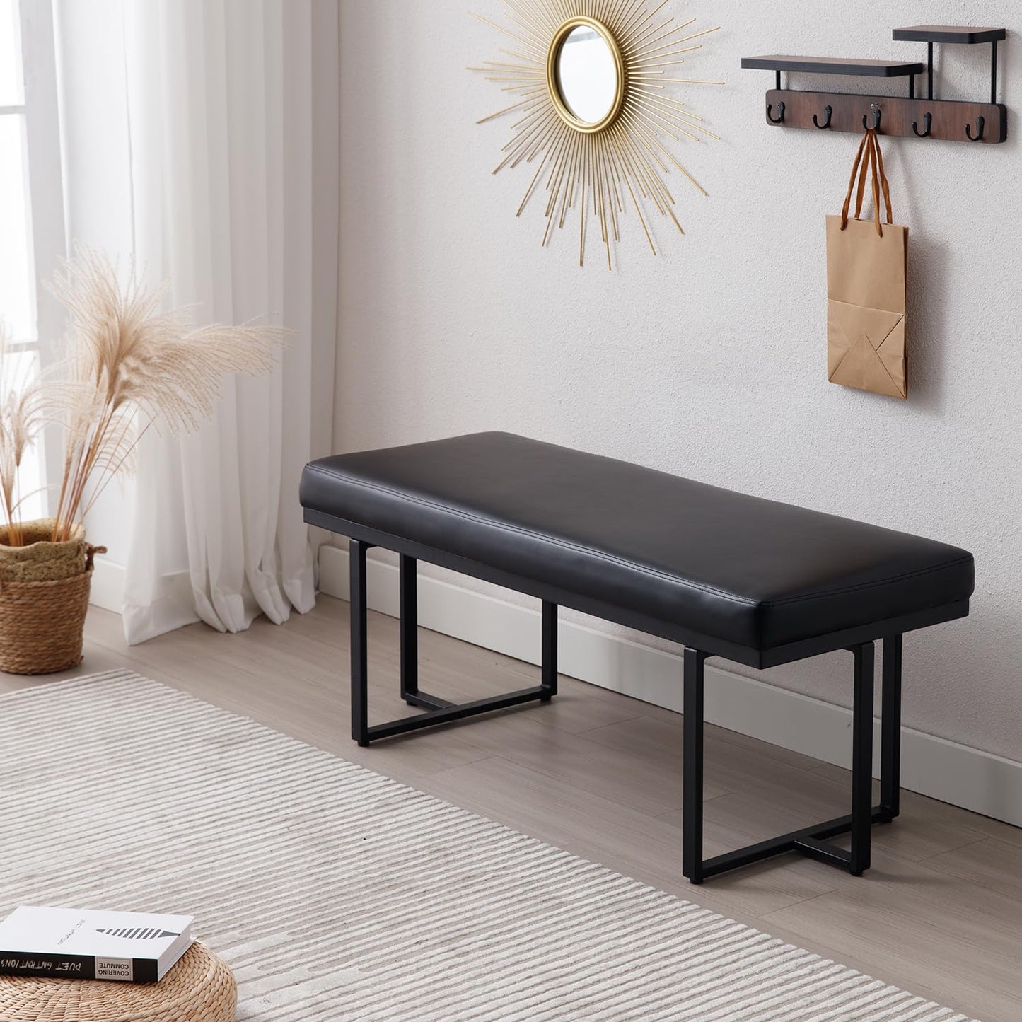 Black bench in a room with a mirror, hooks, and decor items.