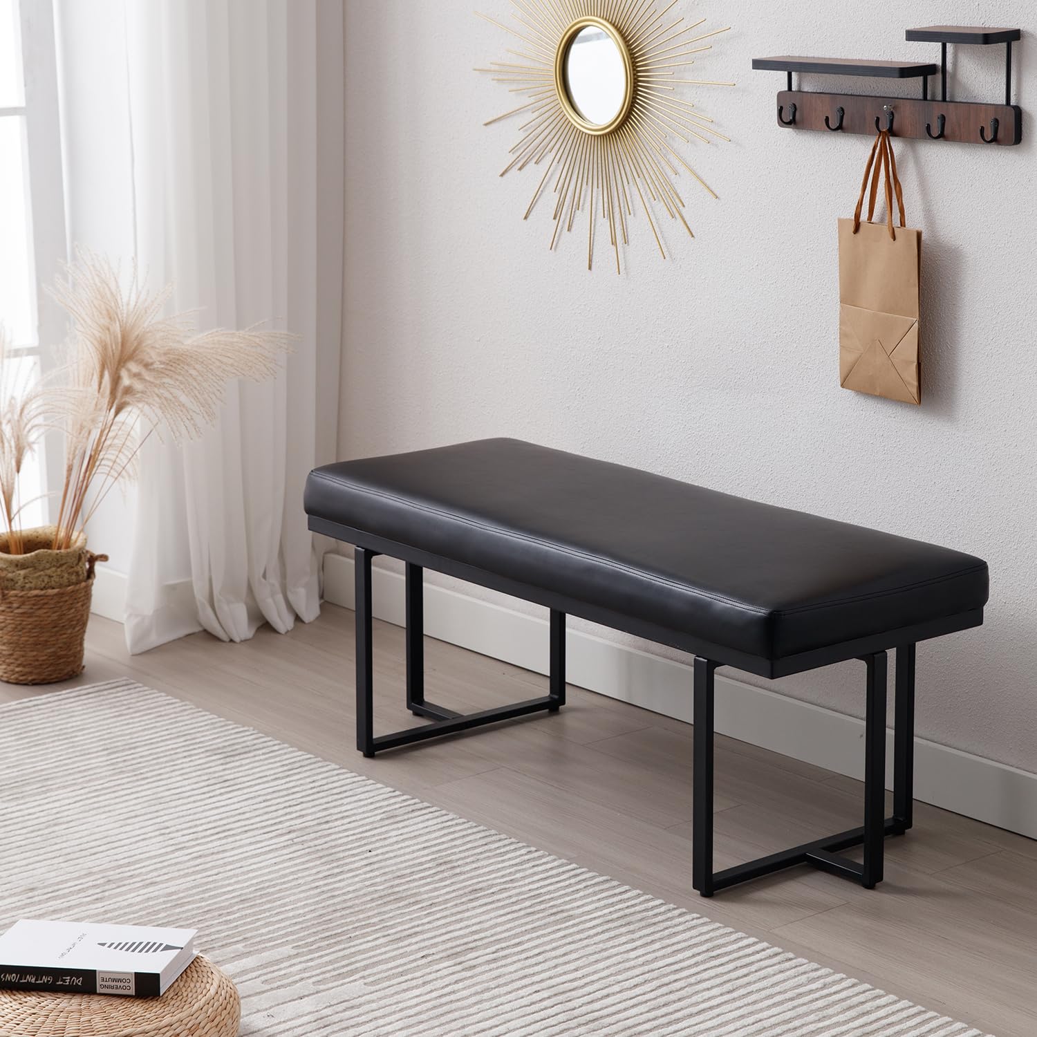 Black bench in a room with a mirror, hooks, and decor items.