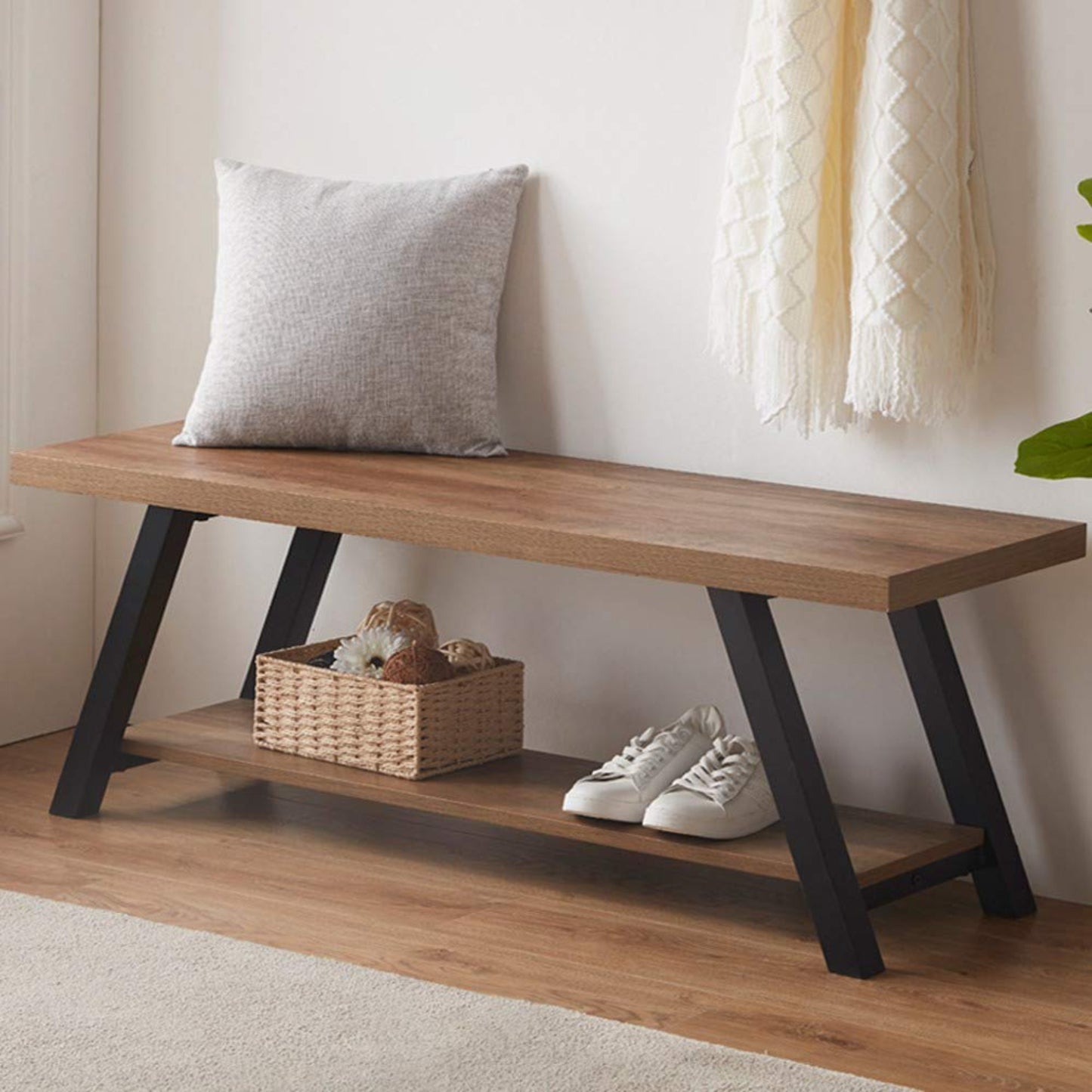Wooden bench with a cushion, basket, and shoes in a room setting.