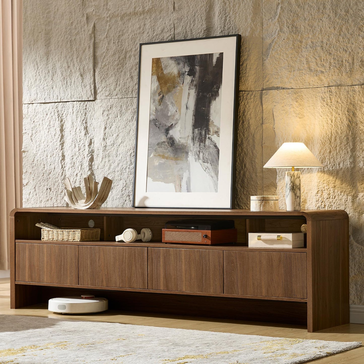 Wooden entertainment console with decorative items against a textured wall.